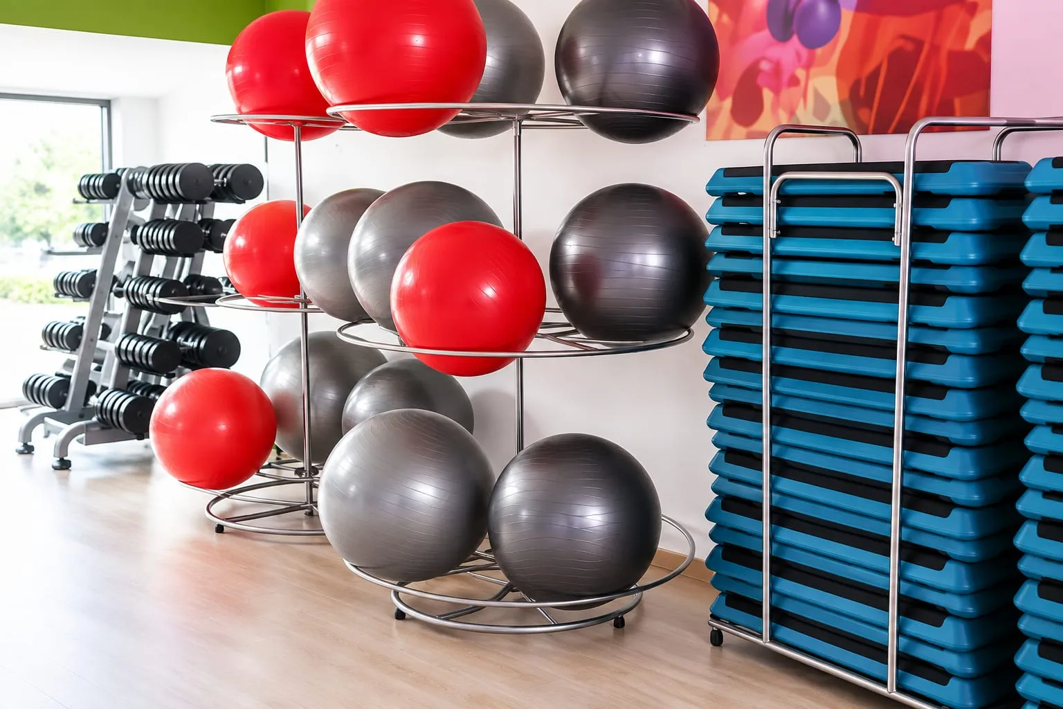 Matériel de cours collectifs avec ballons de gym, haltères et plateformes de step.